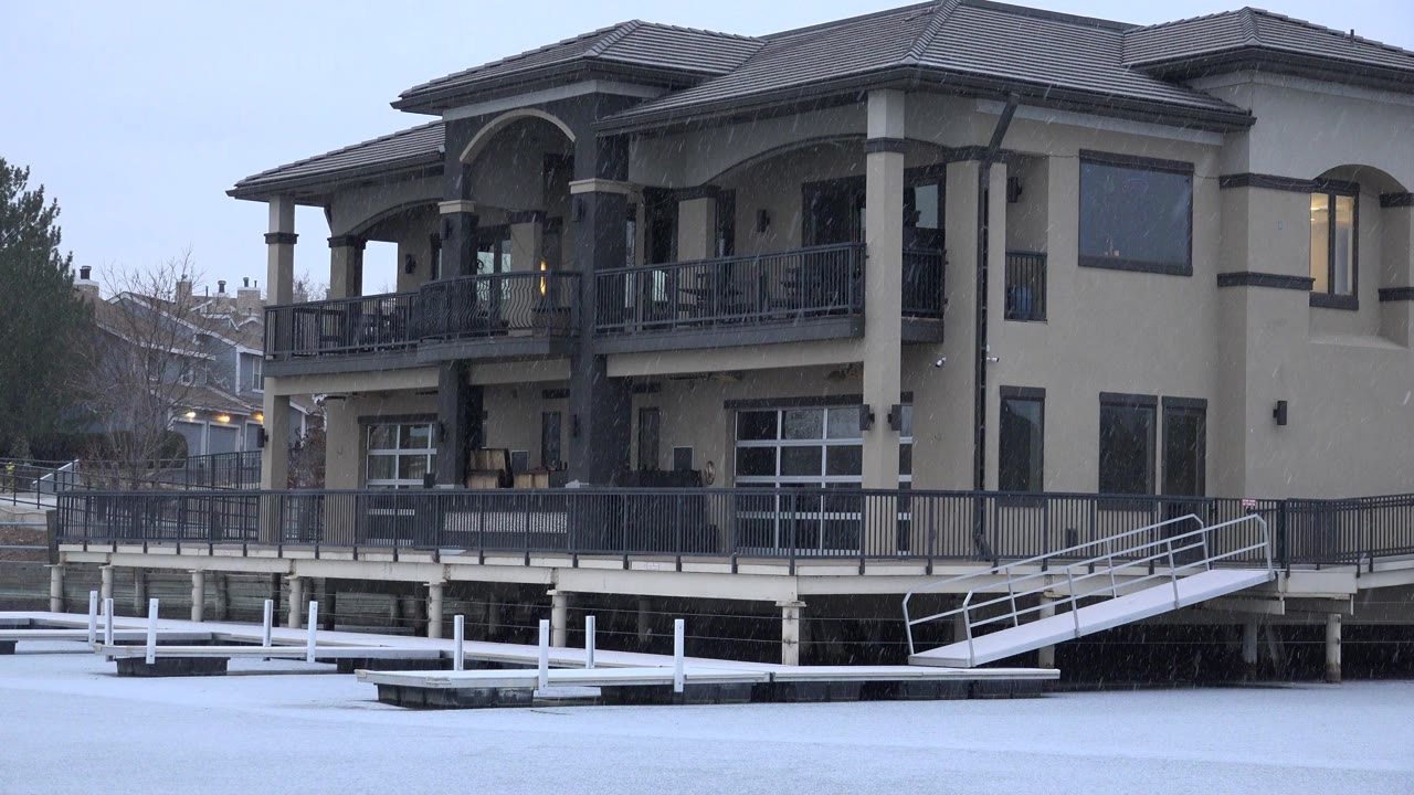 Large two-story house behind snowy foreground and white dock railings.