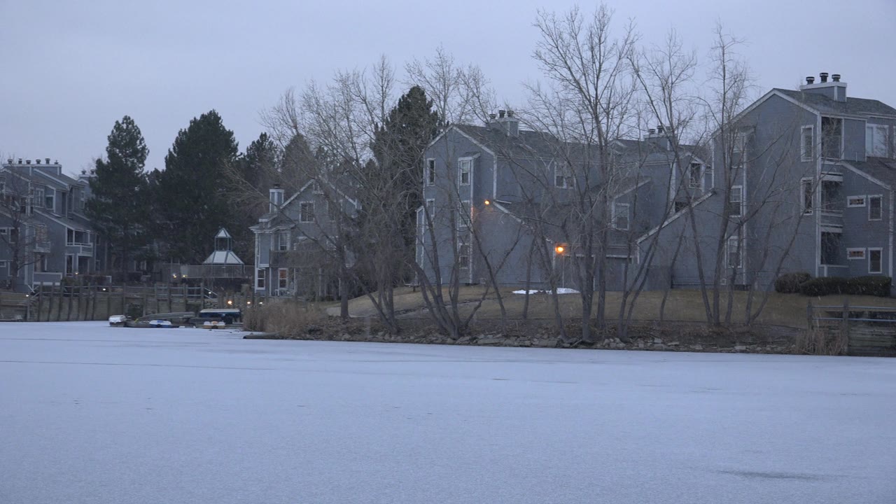 Riverside homes with bare trees and a lit exterior lamp.