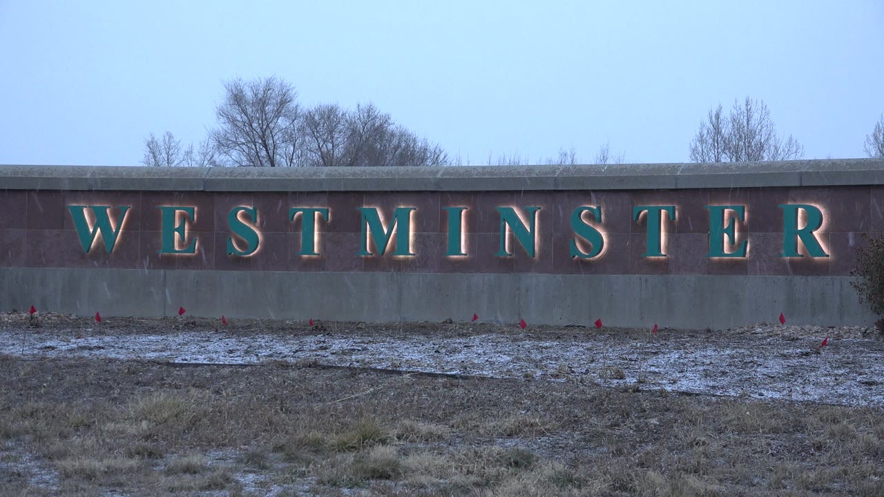 Westminster sign on dark wall under pale sky