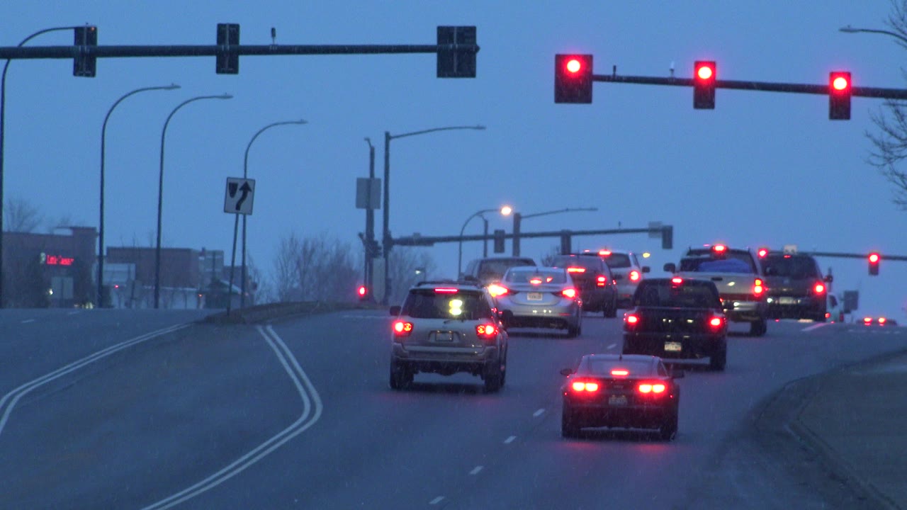 The traffic group sits closer together under red lights in Westminster, Colorado, with glowing brake lights, a center lane sign, and no visible people.