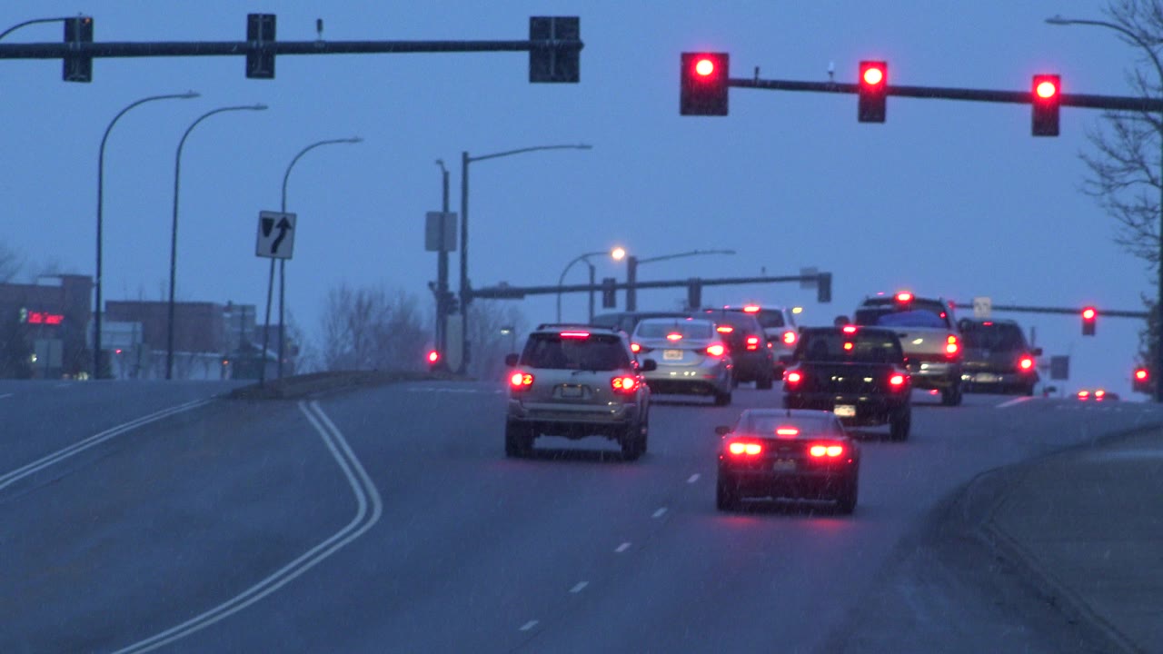 Cars wait near the crest of the road while a red light holds traffic.