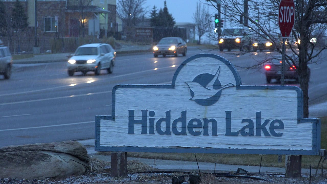 Hidden Lake roadside sign beside traffic on a wet road