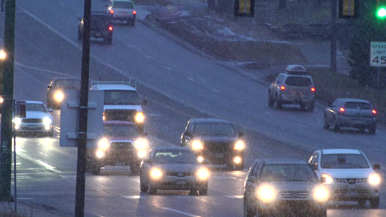 Cars with headlights on approach on a wet winter road.