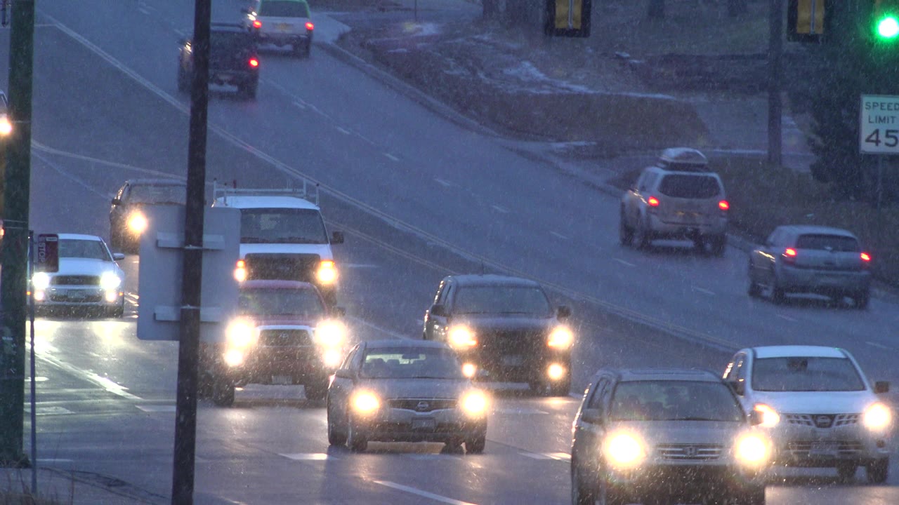 Several vehicles continue along the wet Westminster, Colorado roadway, including a pickup truck near the center and no visible people.
