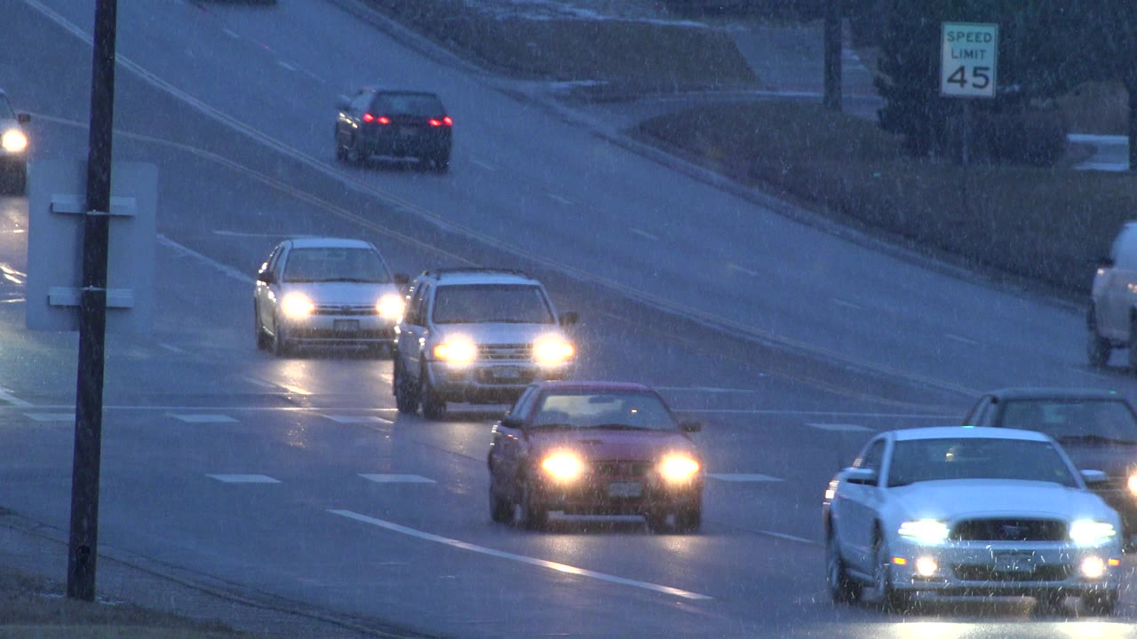 Cars continue along the wet Westminster, Colorado roadway, with bright headlights reflecting across the lanes and no visible people.