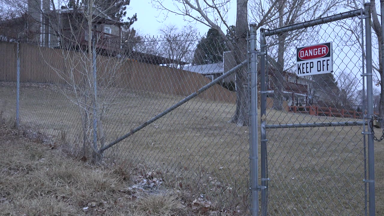 A Westminster, Colorado chain-link gate with a Danger Keep Off sign on the right, leafless trees behind the fence, and no visible people.