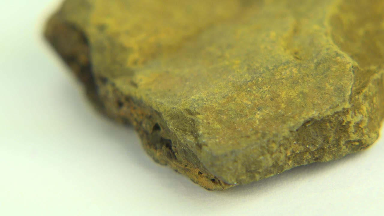 Close view of a green-brown rock corner with a rough porous edge on a pale background in Westminster, Colorado, with no visible people.