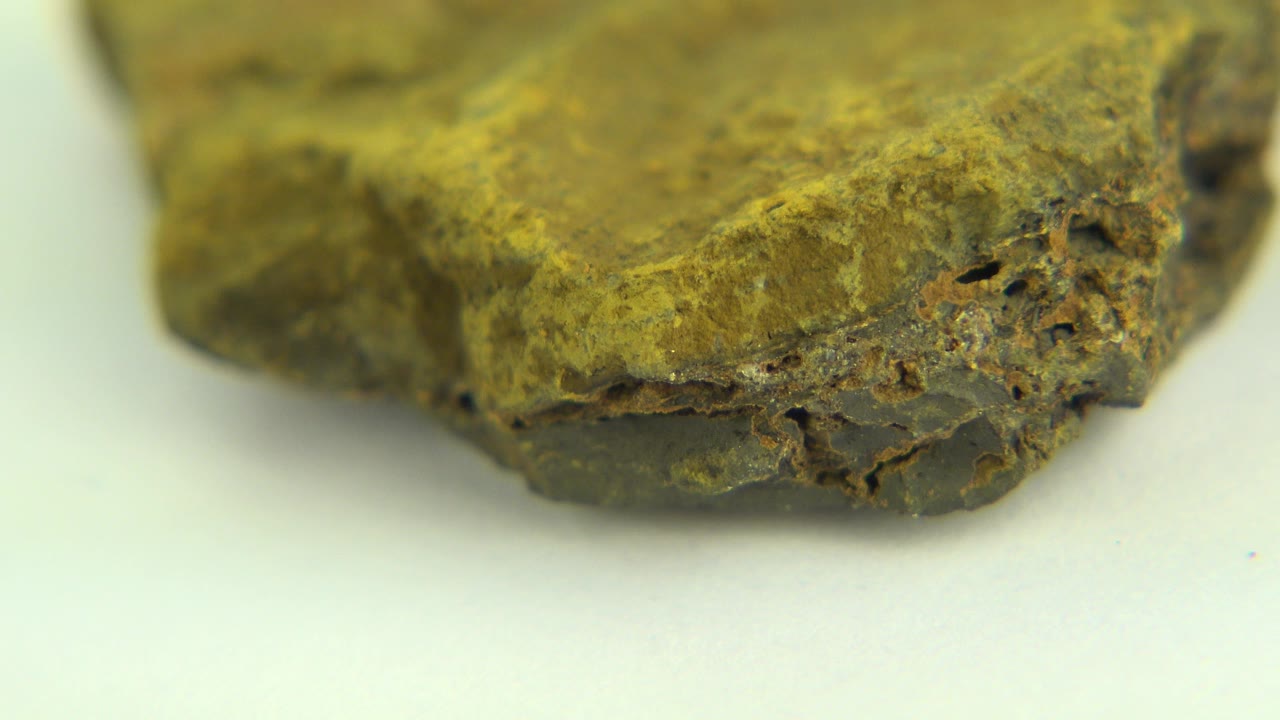 At 0:01, the same rough rock in Westminster, Colorado is angled slightly differently, showing a darker pitted corner against the pale tabletop with no visible people.