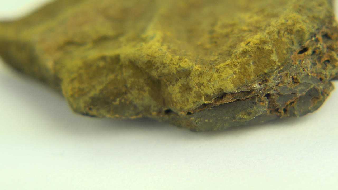 Close-up of the rock with a flatter front edge and dark porous areas.