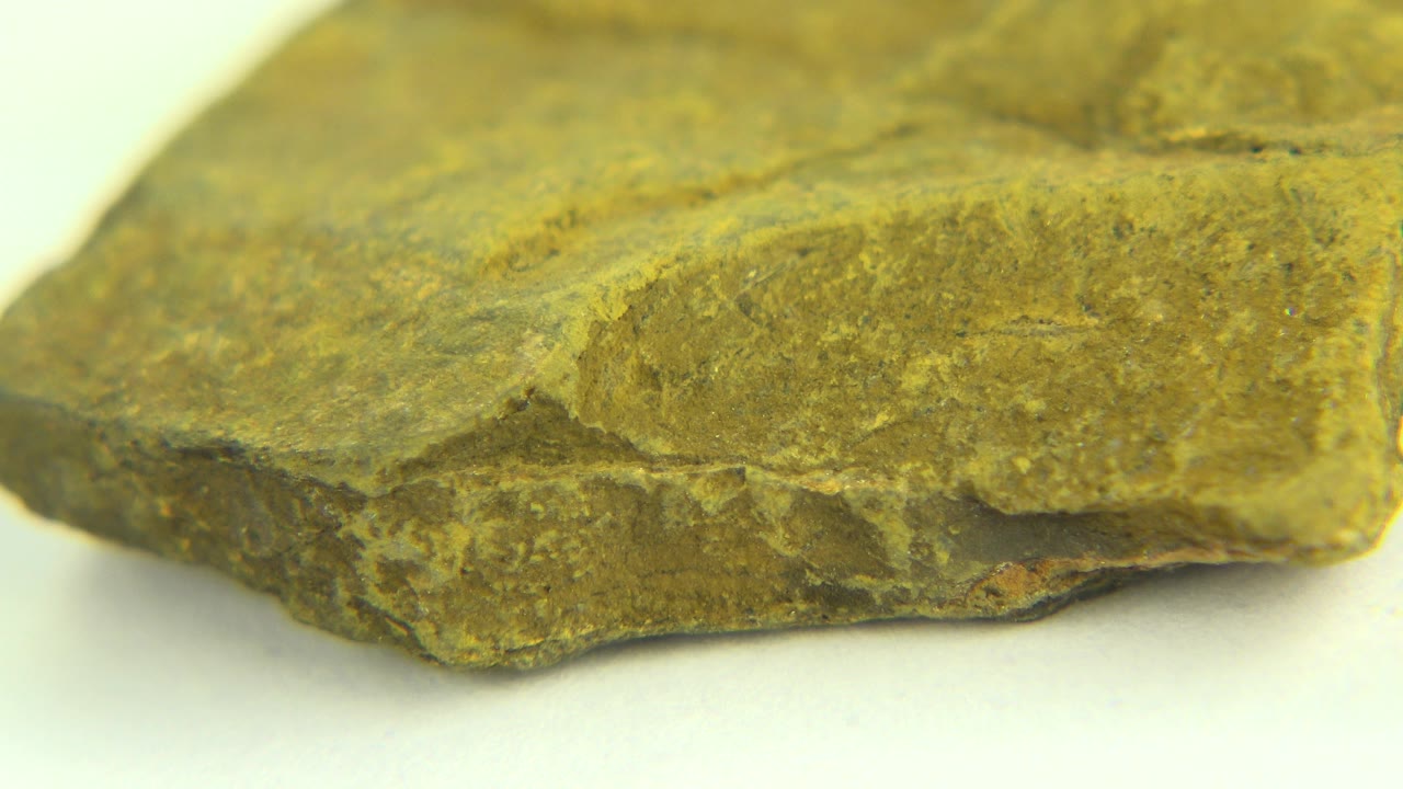 Side close-up of the green rock with a pitted lower edge.