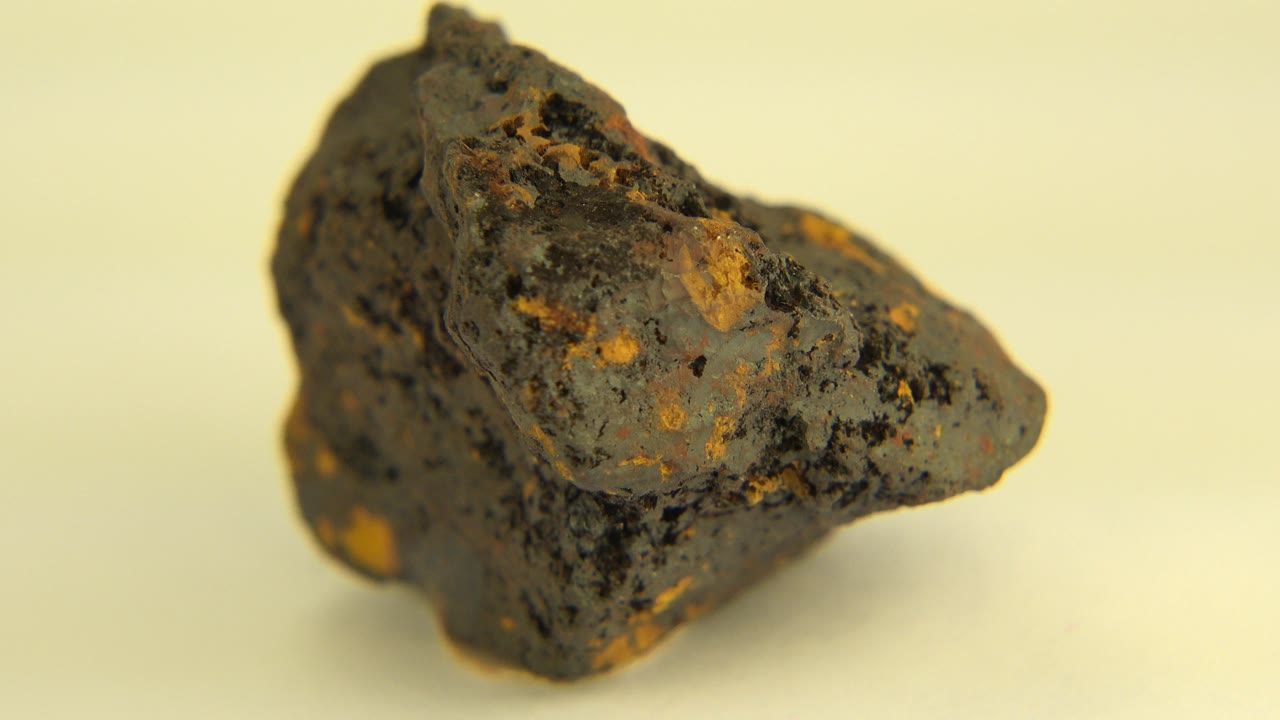 At 0:00, a rough brown rock with dark speckles and gold-colored patches is shown close up on a pale tabletop in Westminster, Colorado, with no visible people.