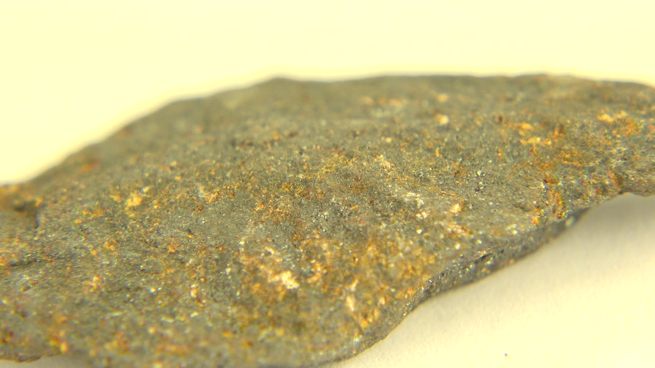 Irregular rock-like piece crossing the frame against a pale background.