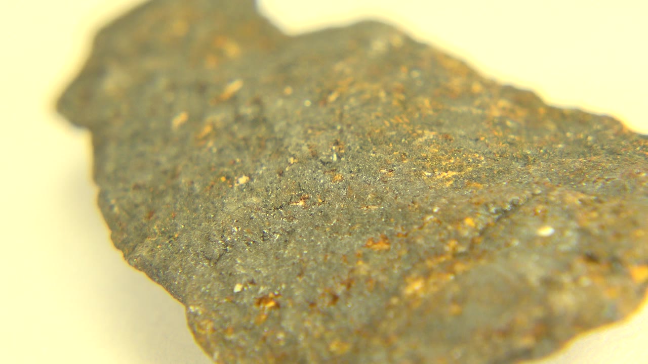 A close view of the rock in Westminster, Colorado shows a broad gray surface with small gold and rust flecks, soft focus, and no visible people.