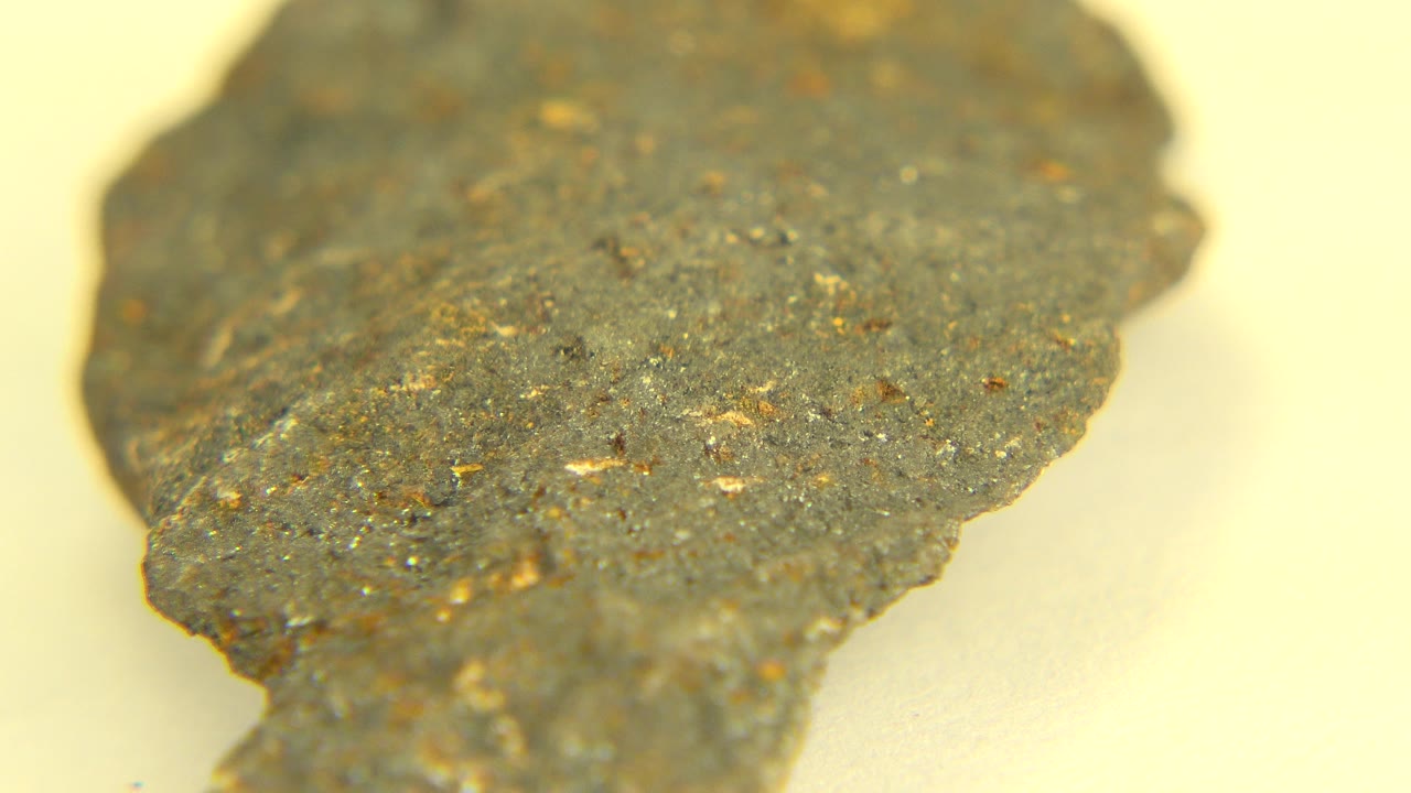 Centered macro-style view of the dark speckled rock in Westminster, Colorado, with rough orange-brown flecks visible and no visible people.