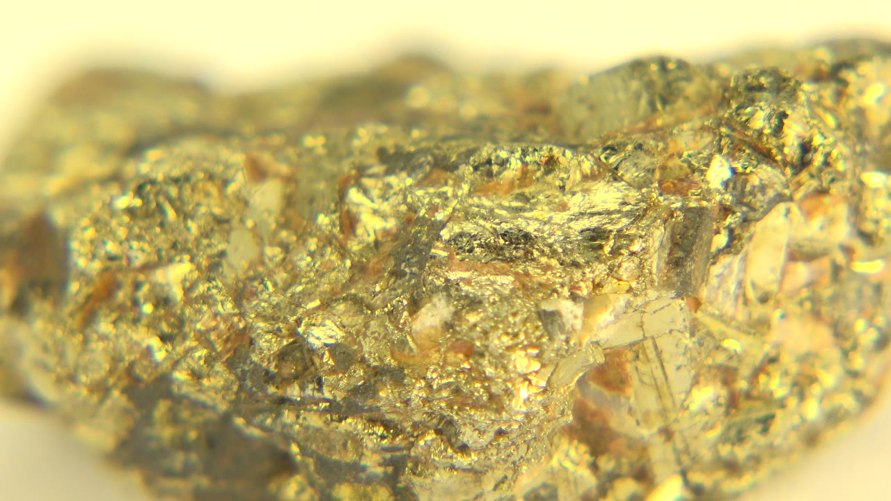 Extreme close-up of a gold-toned crystal-encrusted rock on a pale hard surface in Westminster, Colorado, with soft warm light and no visible people.