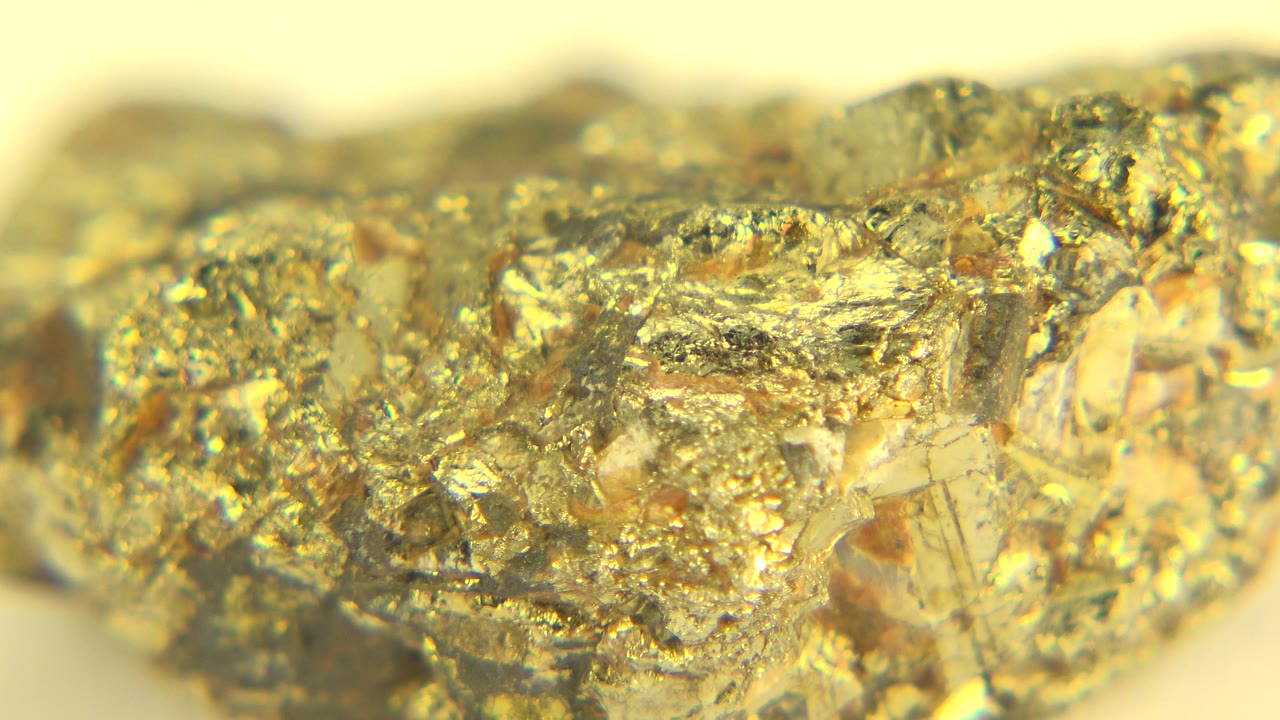 Close macro view of jagged gold and clear crystal facets across the rock in Westminster, Colorado, with a blurred pale background and no visible people.