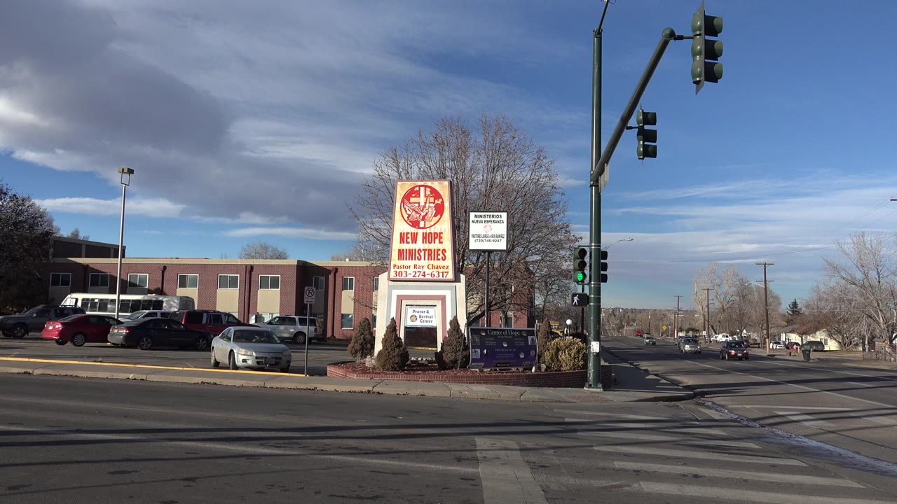 Wide roadside view of New Hope Ministries sign near traffic lights and cars.