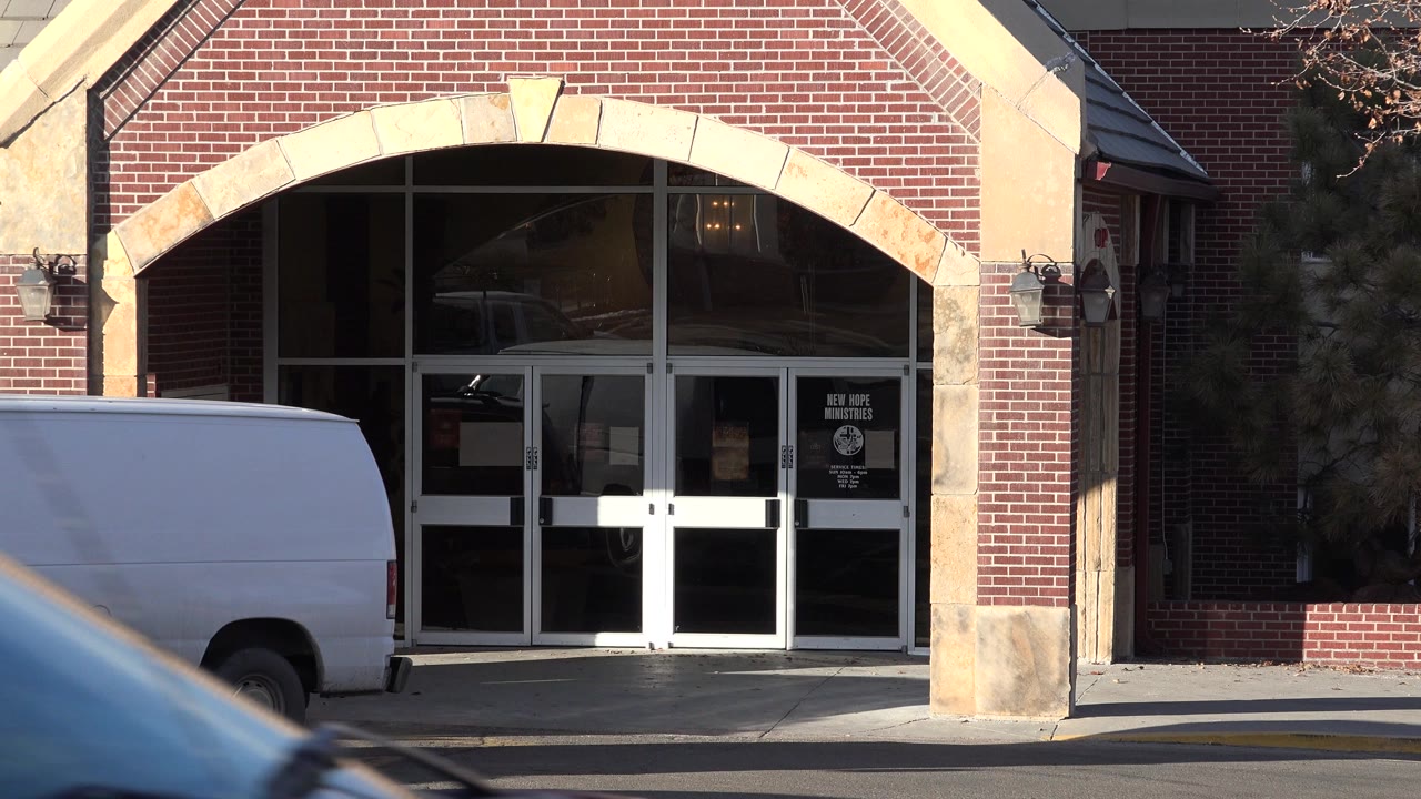 Brick church entrance partly blocked by a white van and a passing car.