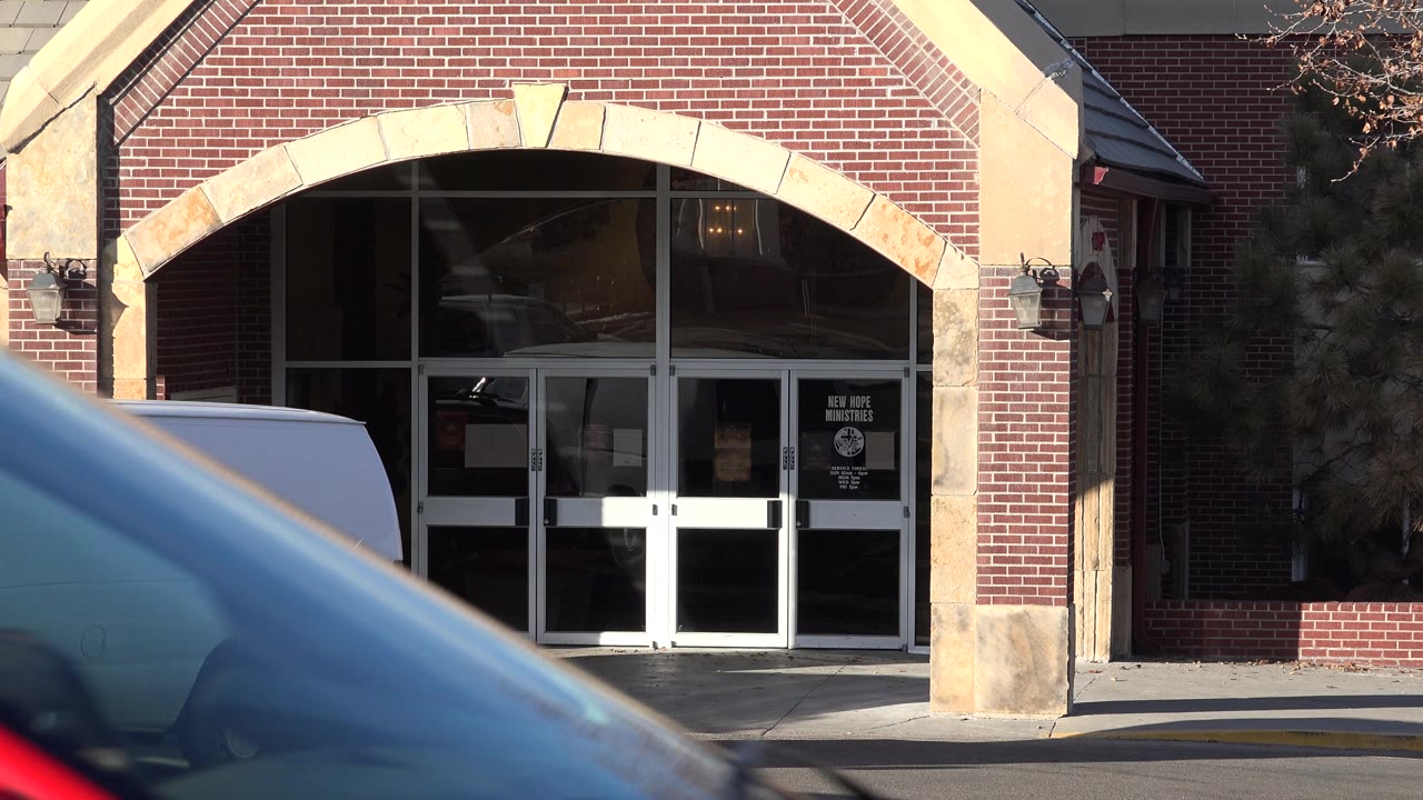Westminster, Colorado church facade with arched entry doors, a white van near the curb, and a blurred vehicle crossing the lower left foreground.