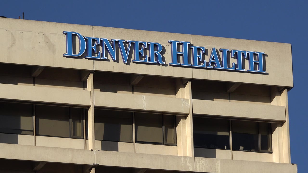 Close low-angle view of Denver Health signage on a concrete building.