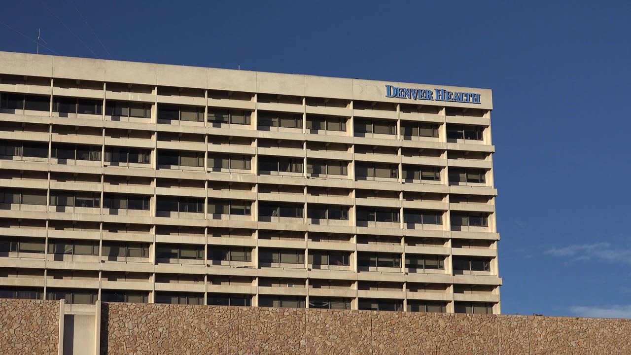 Upper facade of the Westminster, Colorado building fills the frame, with repeating window bays, roofline equipment, Denver Health signage, and no visible people.