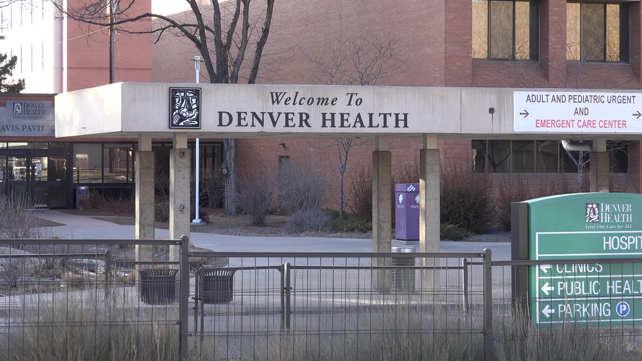 Hospital facade with green direction sign partly cropped at right.