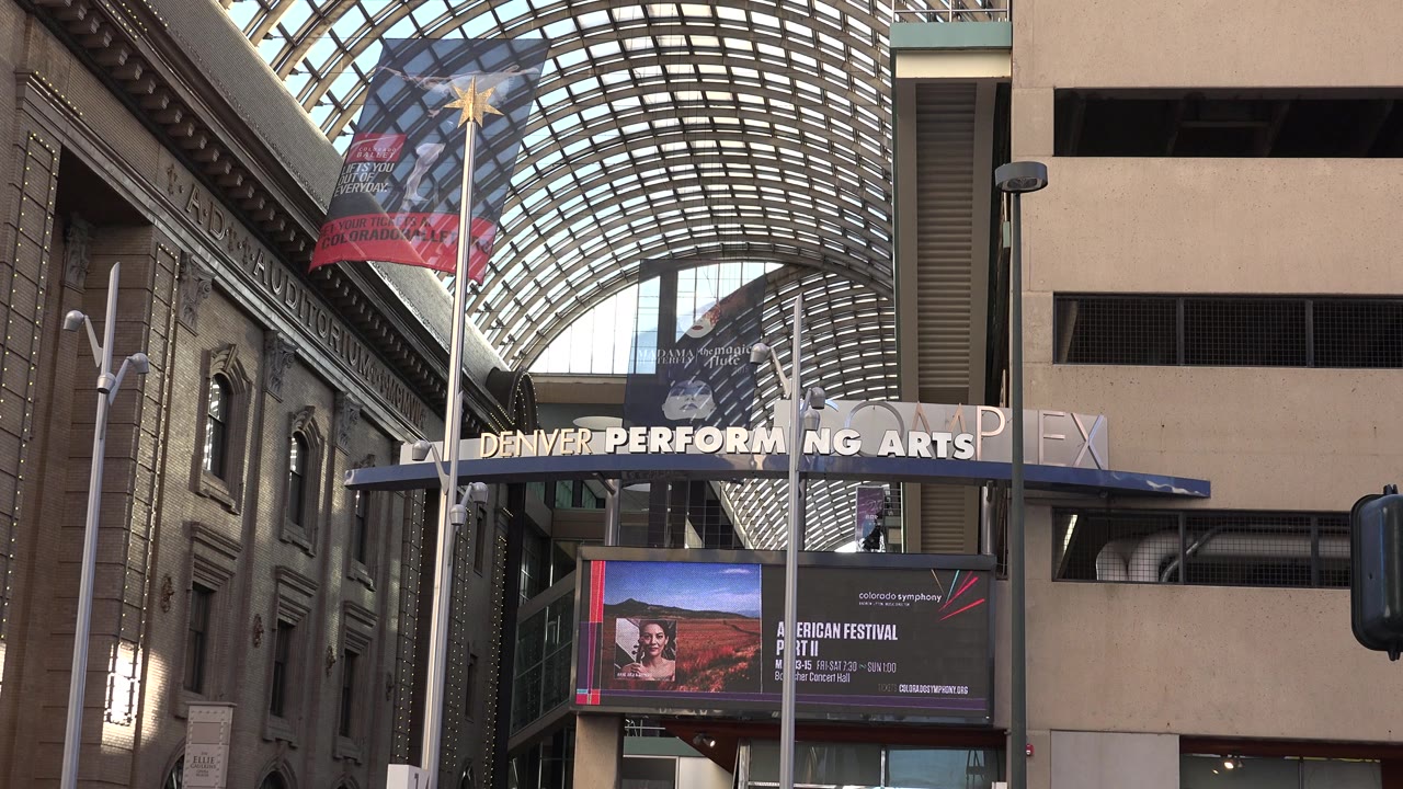 Covered plaza entrance with glass roof and event signage