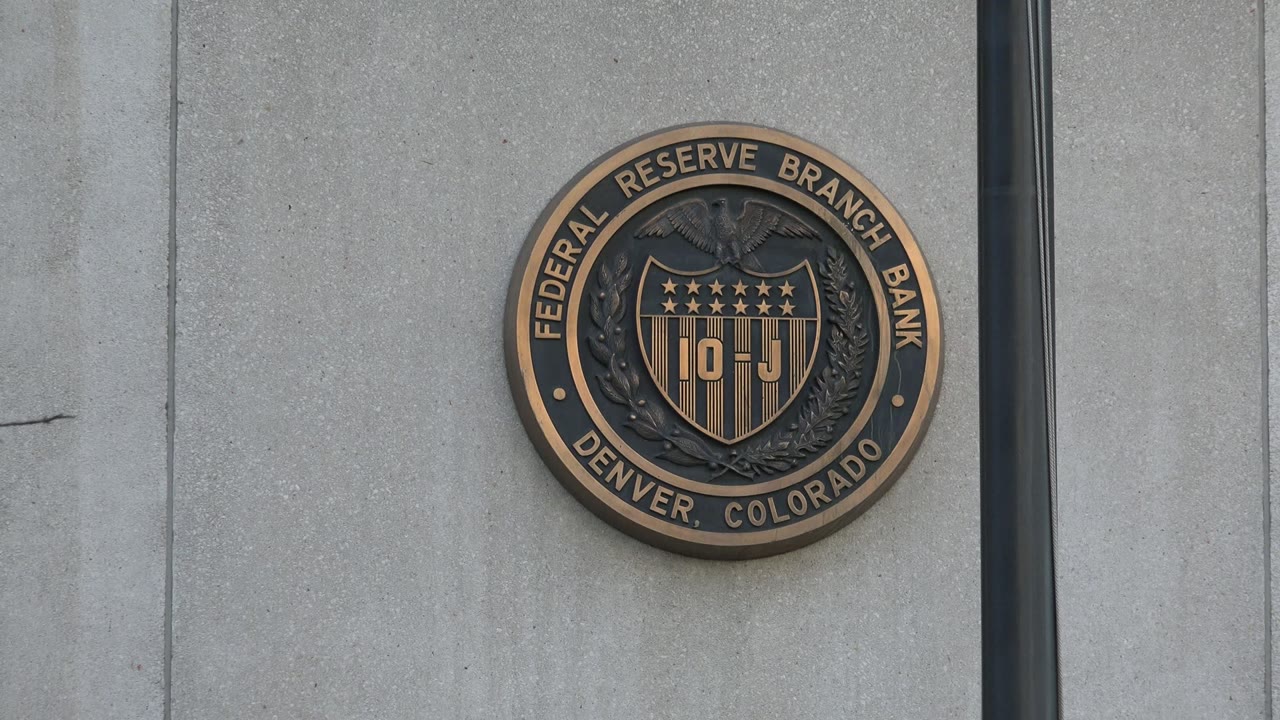 Close facade view in Westminster, Colorado, showing the Federal Reserve Branch Bank seal centered between concrete wall seams and a dark vertical pole, with no visible people.
