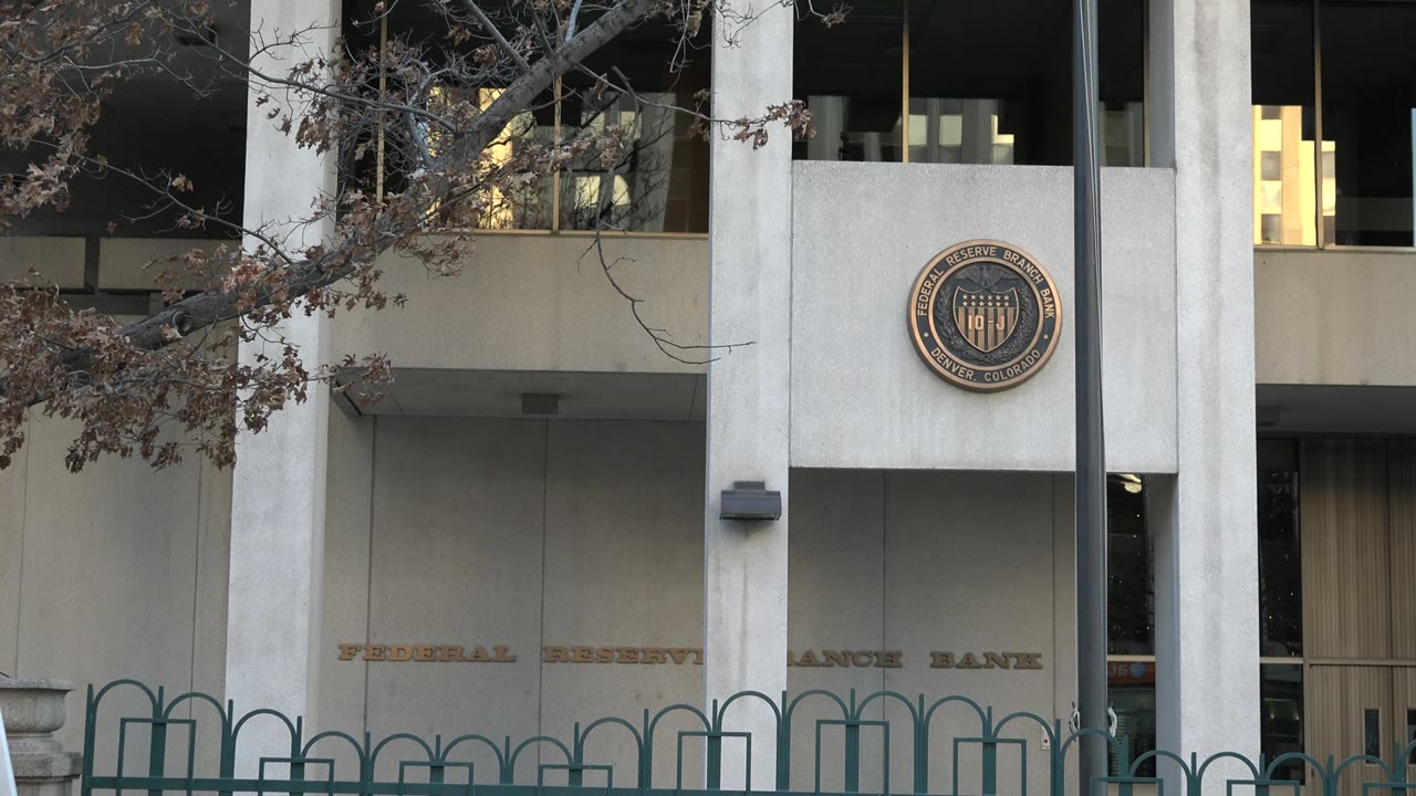 Concrete public building facade with columns, railings, trees, and a circular seal.