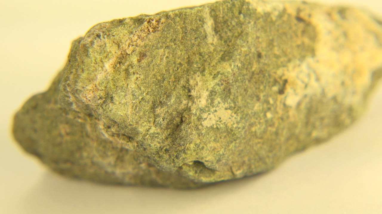 Gray-green rock rotated to show a long side with white patches.