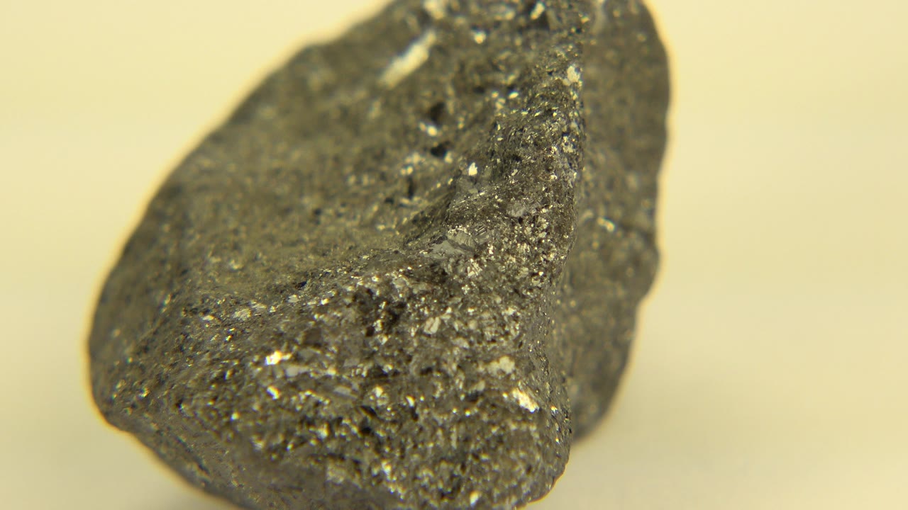 Close-up of a gray porous rock in Westminster, Colorado footage, angled with a pointed front edge and sparkly mineral flecks, with no visible people.