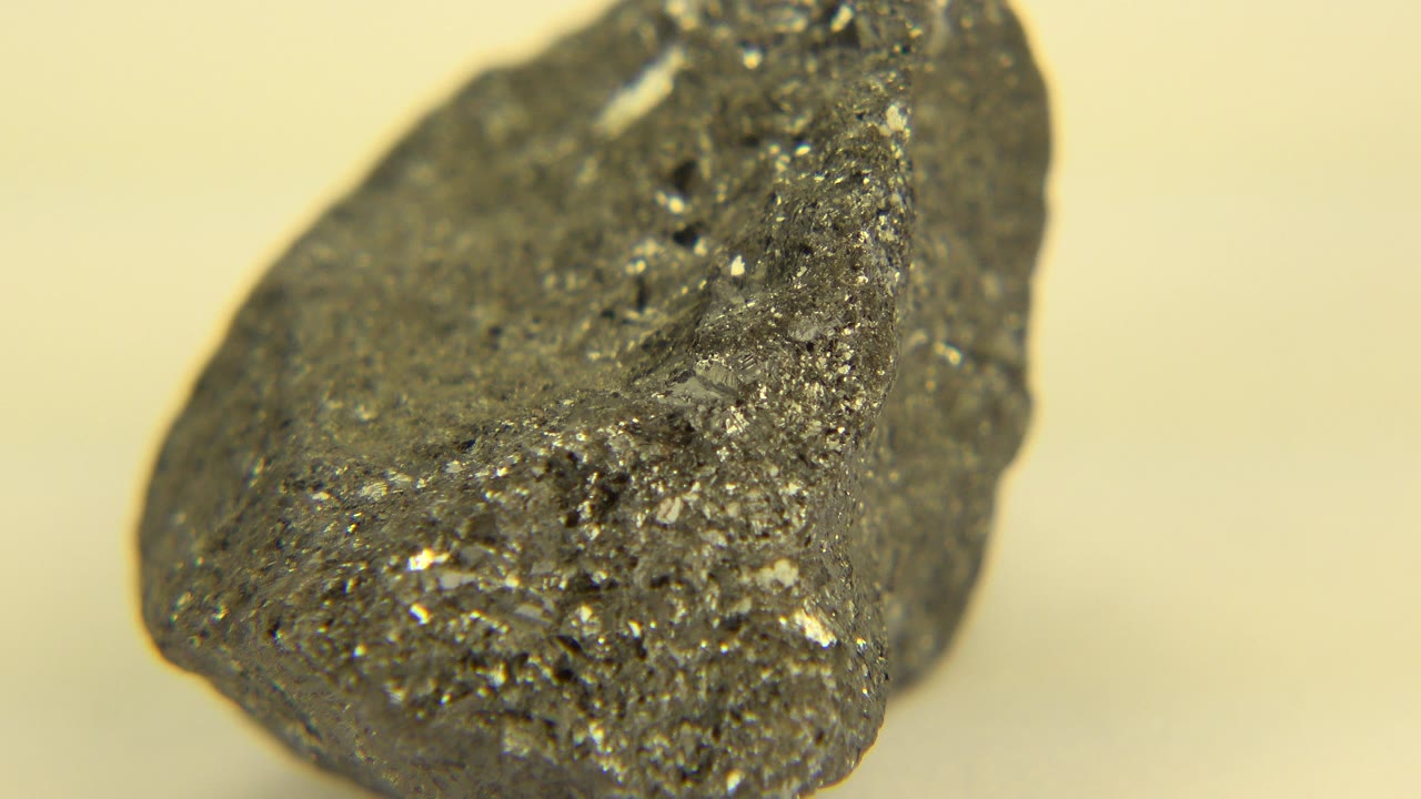 A tight Westminster, Colorado close-up shows the gray rock slightly shifted in view, with a bright ridge of sparkly sediment and no visible people.