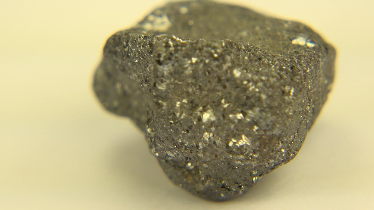 Gray rough rock close-up on a pale yellow-white surface.