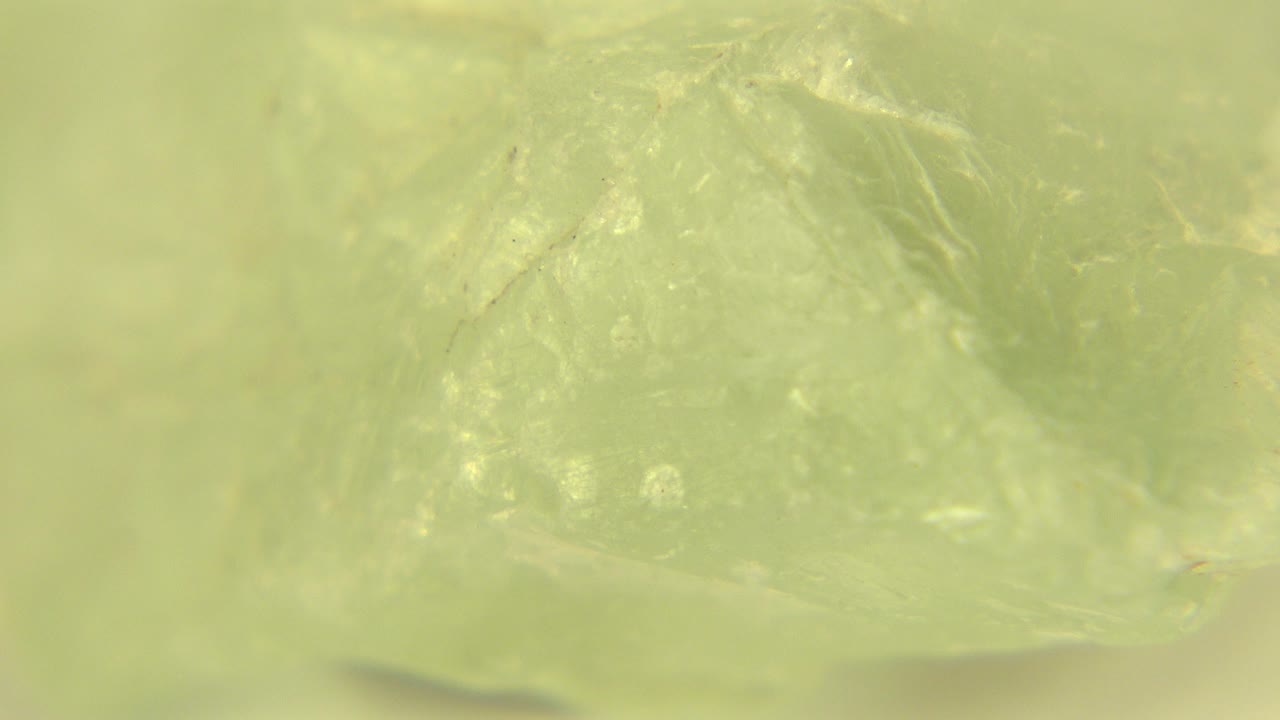 Pale green gemstone seen in soft macro focus in Westminster, Colorado, with cloudy facets and no visible people.