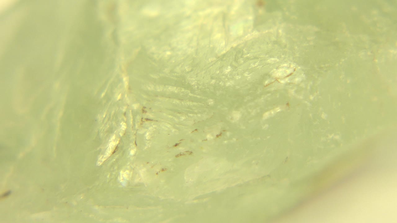 Extreme close-up of a pale green translucent rock in Westminster, Colorado, with soft yellow-green light, shallow focus, and no visible people.