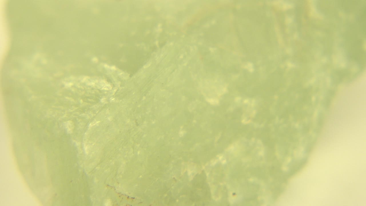 A tight macro frame shows the green gemstone with a darker central facet, fine fissures, and no visible people in the Westminster, Colorado clip.