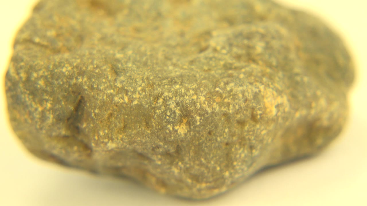 Opening close-up of a rough grey and golden rock surface in Westminster, Colorado, with soft warm light and no visible people.