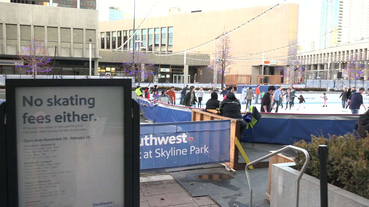 Outdoor skating rink with foreground sign and sponsor barrier.