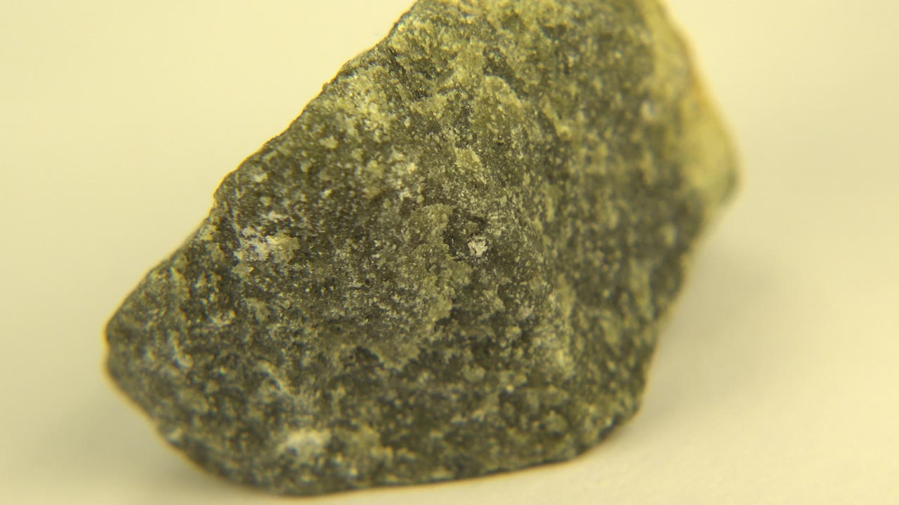 Speckled dark rock remains large in frame on the pale surface in Westminster, Colorado, with a slightly shifted face visible and no visible people.