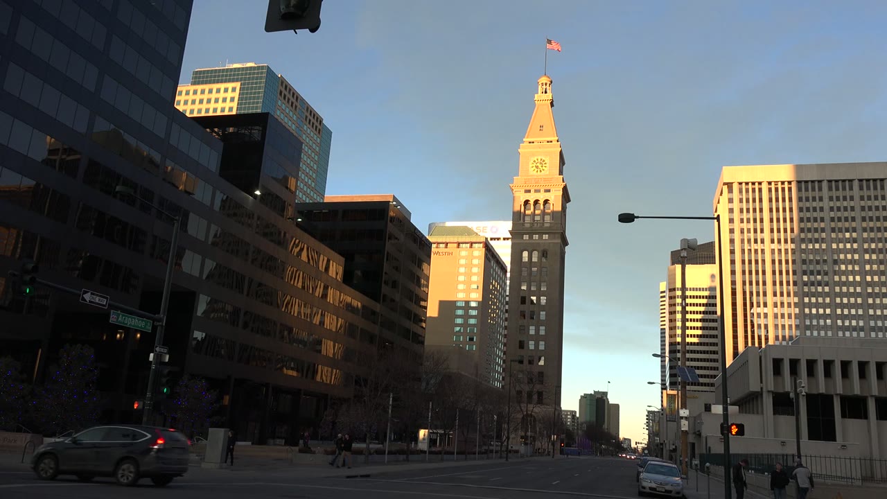 Office towers and city street with a car passing under traffic lights.