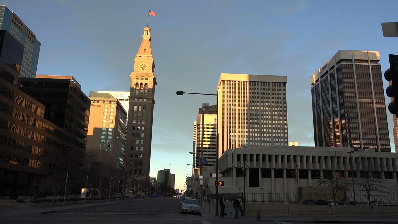 Sunlit clock tower and white office buildings at a city intersection