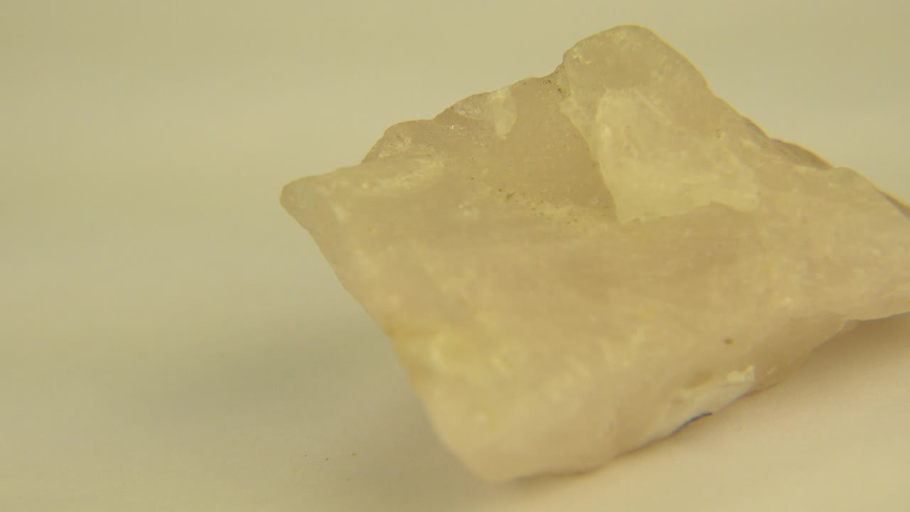 A translucent yellow crystal sits on a pale yellow surface in Westminster, Colorado 2015 footage, angled with a higher ridge at the back and no visible people.