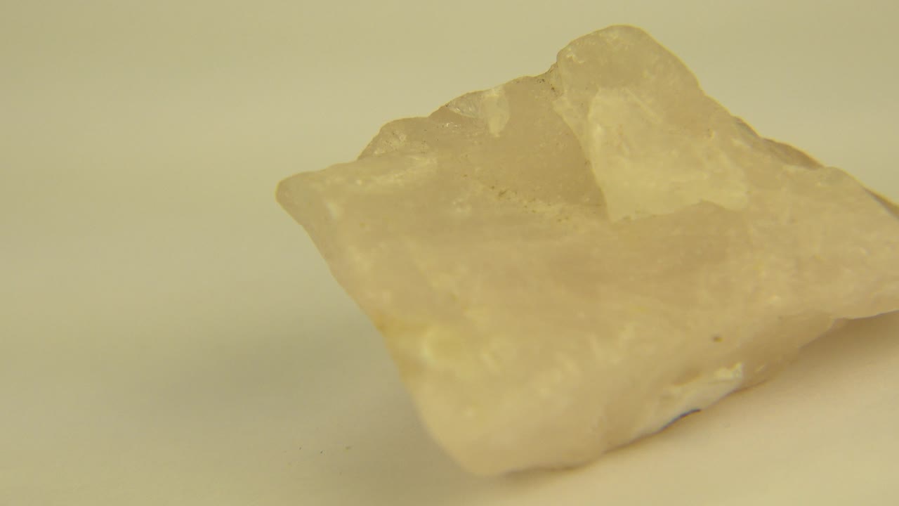The yellow crystal remains large in frame on the pale surface, with the front lower edge and rear peak visible in Westminster, Colorado 2015 footage and no visible people.