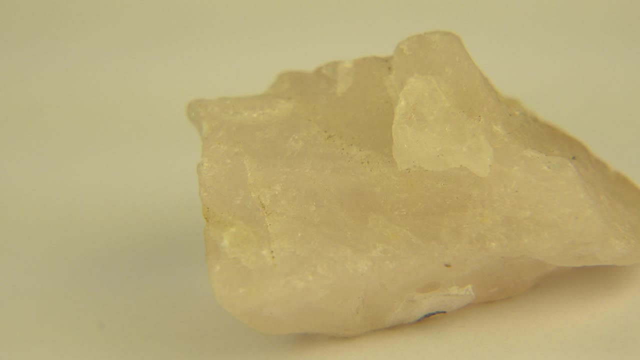 Side view of a translucent yellow crystal on a plain surface.