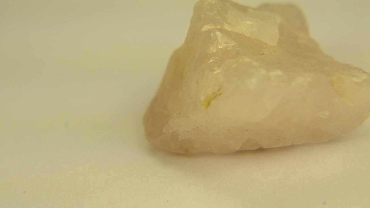 A translucent white rock rests on a white floor in Westminster, Colorado, seen from a low angle with its taller jagged ridge toward the back and no visible people.