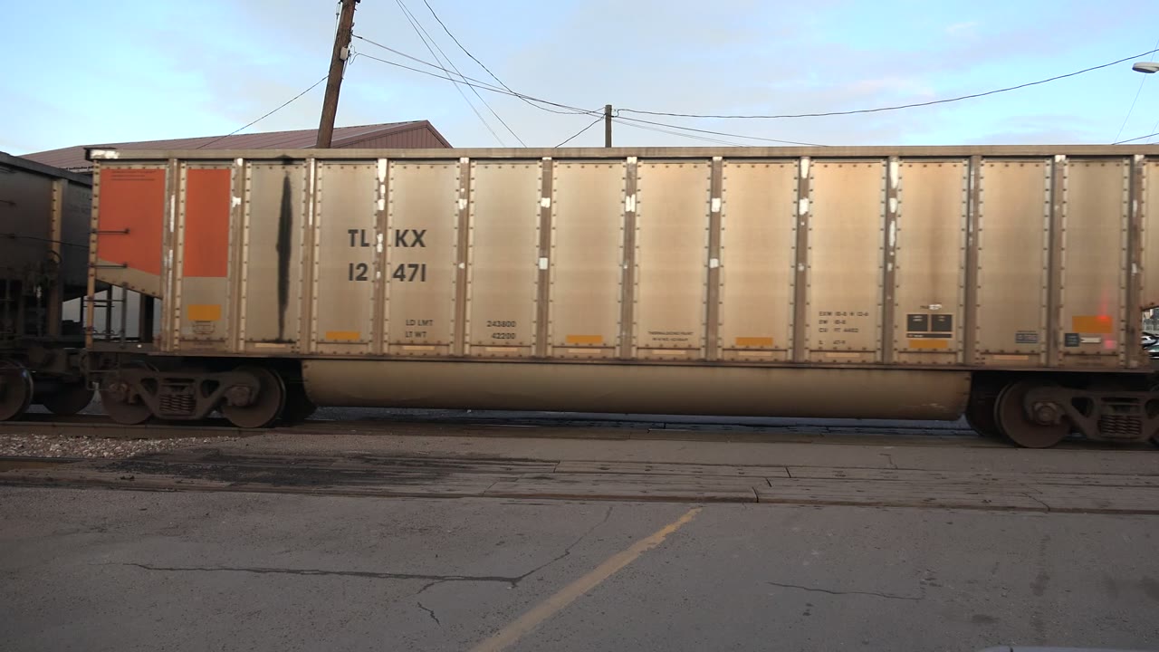 Freight rail car passing broadside at a street crossing.