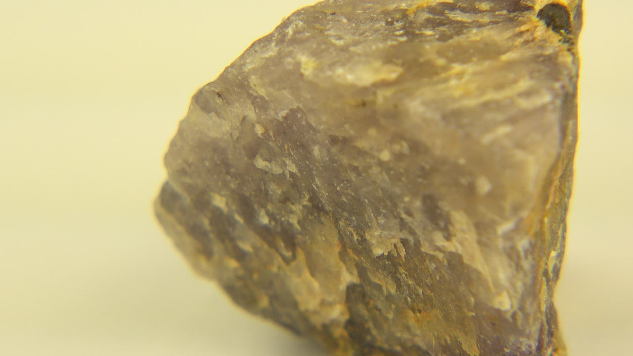 Close-up of a gray-brown cracked stone on a pale background.