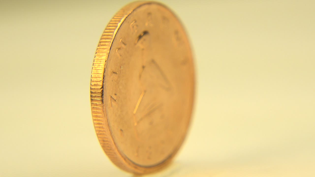The coin remains upright while spinning, with its face still soft and its ridged edge catching warm light, no visible people.