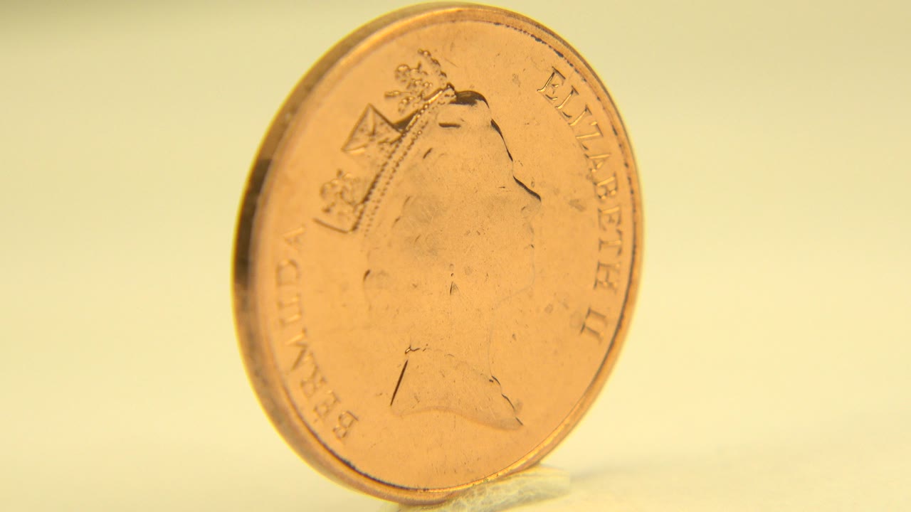 A copper-colored Elizabeth II coin stands nearly upright on a small support in Westminster, Colorado footage, with its portrait side angled slightly and no visible people.