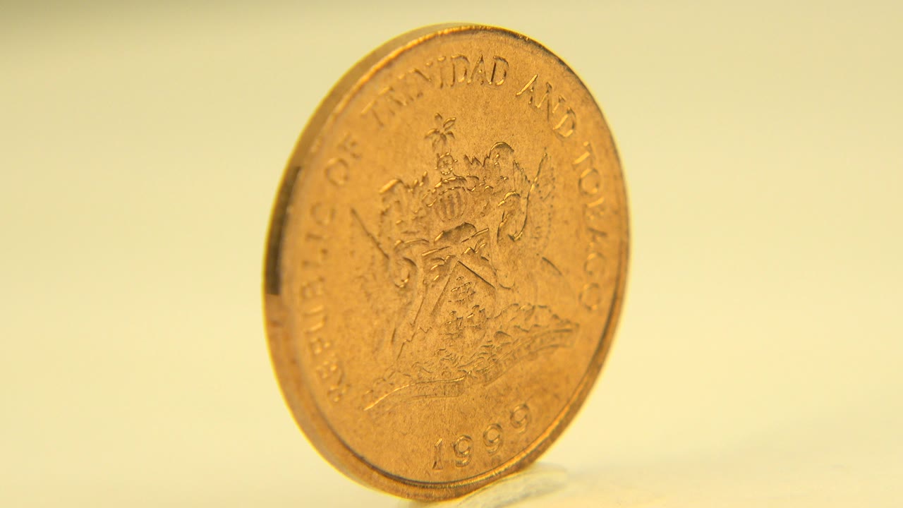 Gold-toned coin seen nearly face-on at the start of a Westminster, Colorado close-up, with warm light, a pale yellow background, and no visible people.